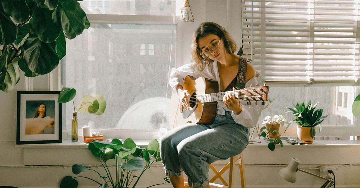 woman playing the guitar in living room